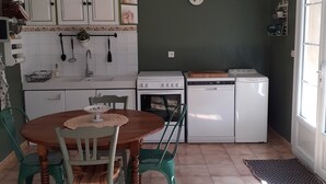 A compact kitchen with white cabinets, a dining table with chairs, and a small window. - 200 meters from the heart of the village, App 55 M² WiFi In a closed courtyard, quiet (Châteauneuf-De-Gadagne)