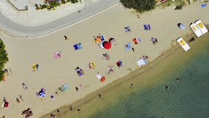 Vue aérienne d’une plage avec des personnes, des parasols et des chaises de plage.