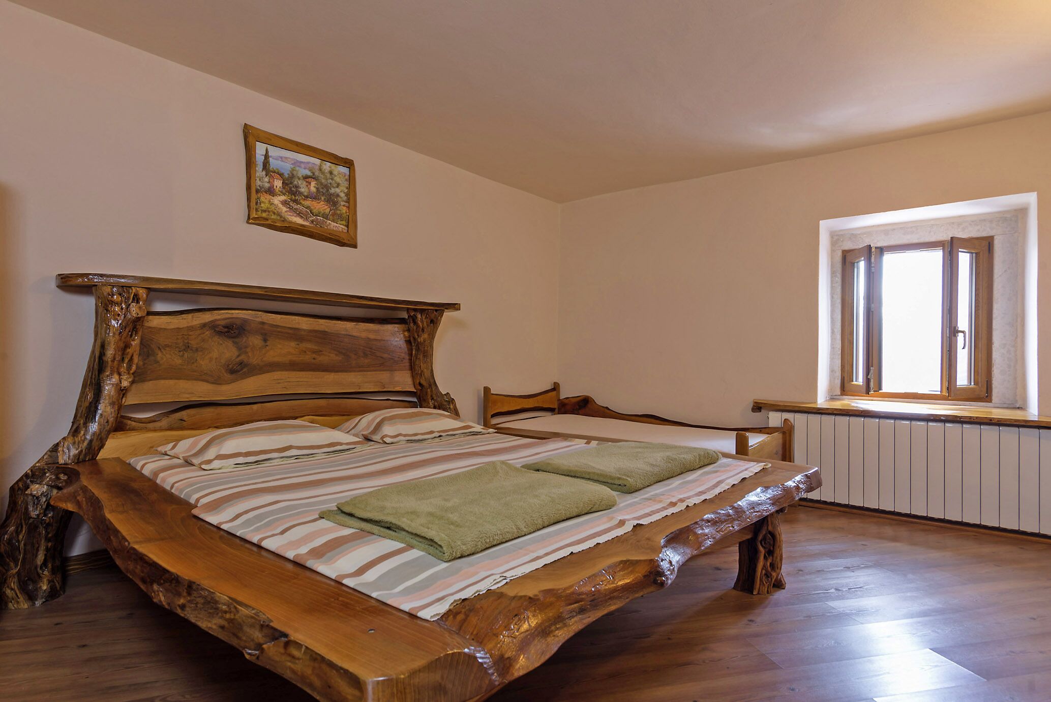 Una cama de madera con un diseño original, una ventana con cortinas y un cuadro en la pared.