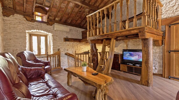 Un salon de style rustique avec un escalier en bois, un canapé en cuir et un téléviseur.