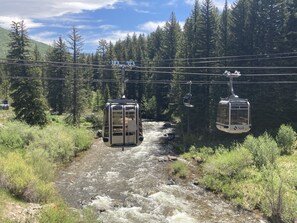 A cable car system over a river with forested hills in the background.
