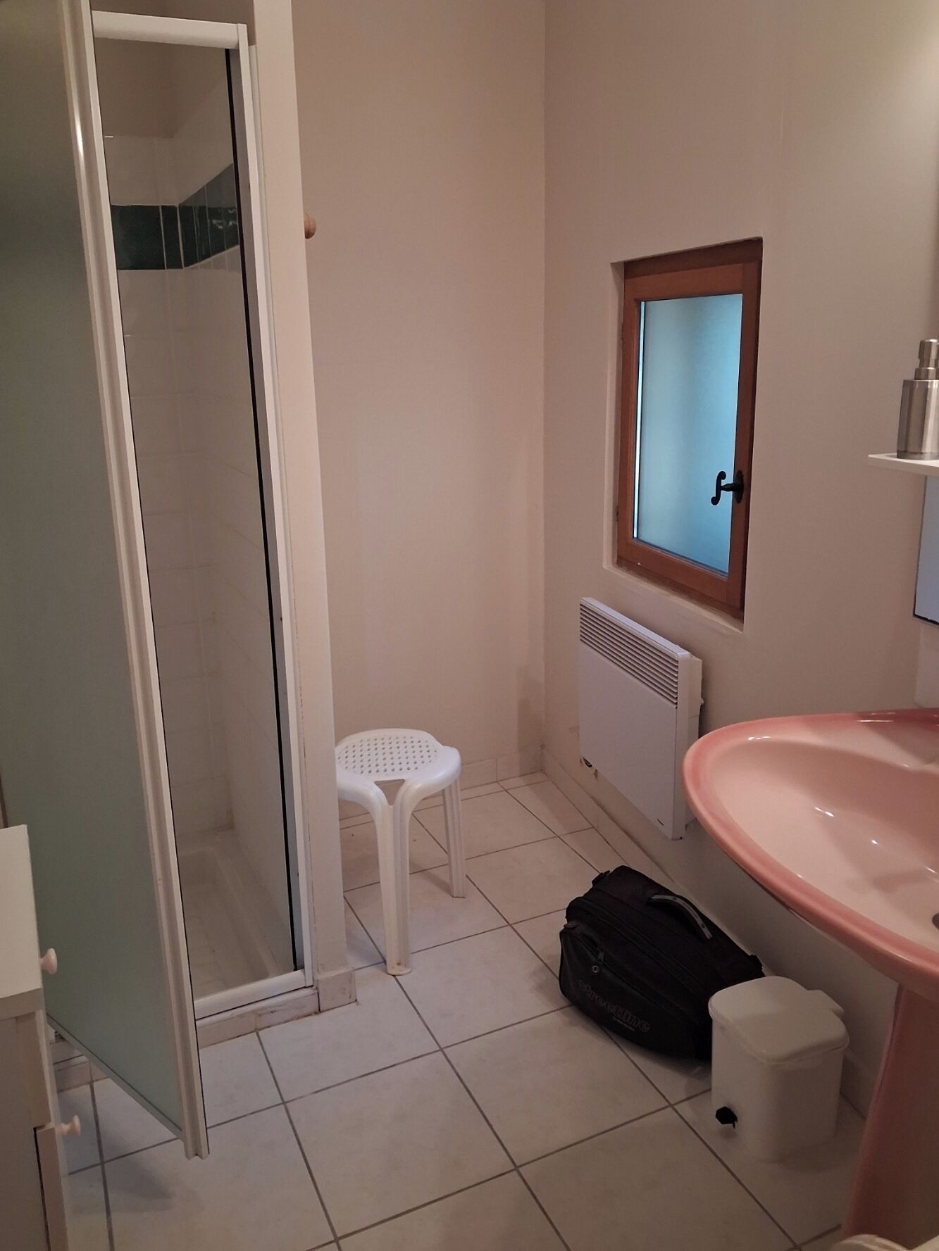 A bathroom with a shower, a toilet, a sink, and a window.