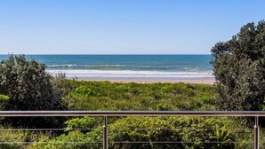 Vista costera con playa, océano y abundante vegetación.
