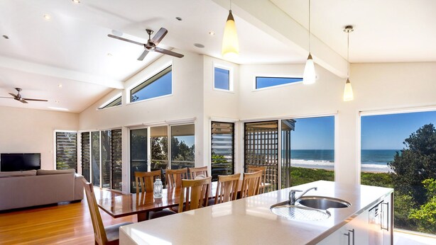 Una cocina moderna con una isla grande, comedor y vista al océano.