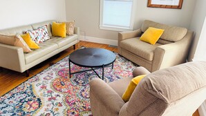 A living room with a beige sofa, a matching armchair, and a coffee table. - Downtown Kennebunk Home  (Kennebunk)