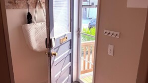 A doorway with a white door, a hanging white bag, a colorful rug, and a view of the outside. - Downtown Kennebunk Home  (Kennebunk)