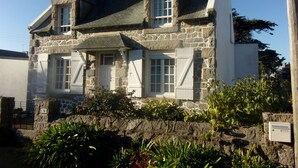 A stone house with a steeply pitched roof, white shutters, and a stone foundation. - House 2-7 people, 150m from the beach Tregastel White Strike, Near Perros-Guirec (Trégastel)