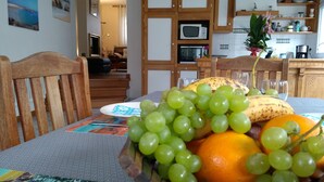 A dining table with a fruit bowl containing grapes, a banana, and an orange. - House 2-7 people, 150m from the beach Tregastel White Strike, Near Perros-Guirec (Trégastel)