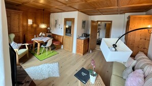 Una habitación acogedora con paredes y techo de madera, un comedor con mesa y sillas, un sofá y una lámpara.