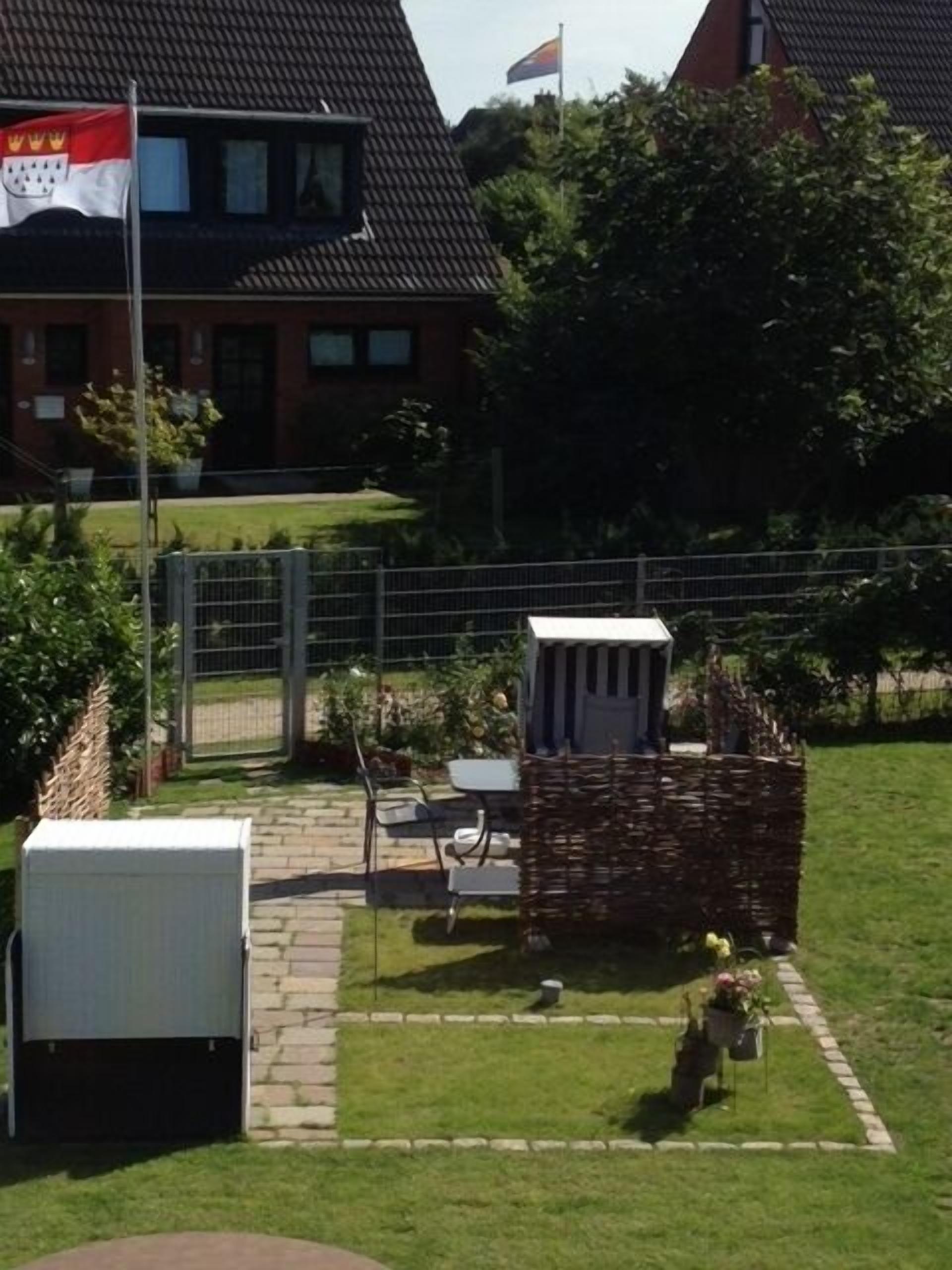 A fenced backyard with a small garden, a white utility shed, and a flagpole with a flag.