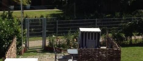 A fenced backyard with a small garden, a white utility shed, and a flagpole with a flag.