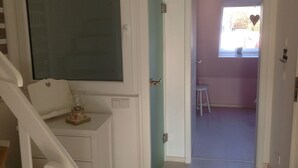 A room with a white staircase, a door leading to a pink room, and a window with a heart decoration. - quiet duplex apartment, modern and bright (Sylt-Ost)