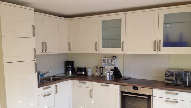 A modern kitchen with white cabinets, a stainless steel sink, a coffee maker, and a built-in oven. - quiet duplex apartment, modern and bright (Sylt-Ost)