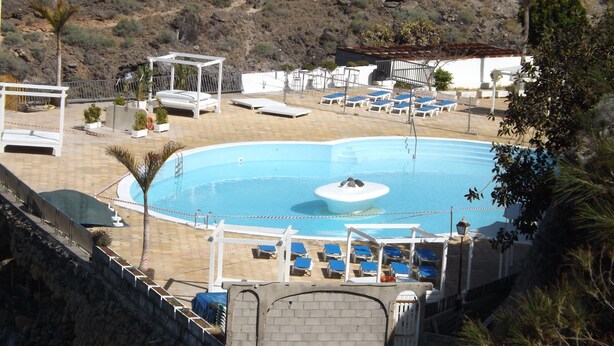 En swimmingpool med liggestole og en lille  ø.