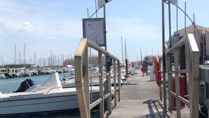 A wooden pier leading to a marina with boats docked. A sign above reads "PONTON V".