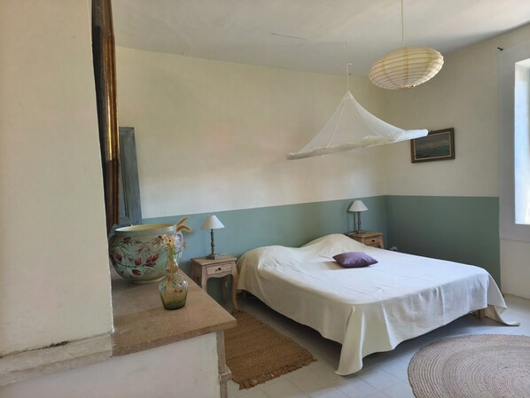 A bedroom with a bed, bedside tables, a hanging light fixture, a vase, and a painting on the wall. - Quiet village farmhouse with a terrace and garden, (Goudargues)