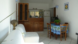 A compact kitchen with wooden cabinets, a refrigerator, and a dining table with chairs. - Furnished T2 (3 stars) with terrace and pool in the Luberon Côté Sud. (La Tour-D'aigues)