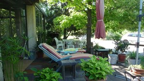A covered patio area with lounge chairs, a table, and potted plants. - Furnished T2 (3 stars) with terrace and pool in the Luberon Côté Sud. (La Tour-D'aigues)