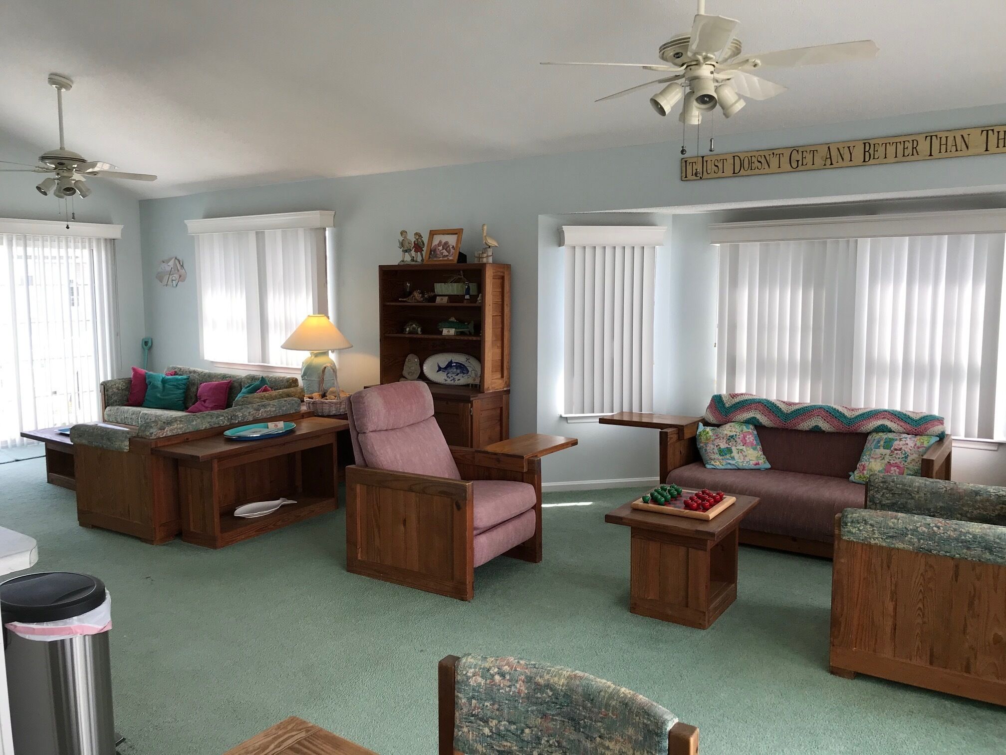 A living room with a ceiling fan, a wooden bookshelf, and a coffee table with decorative items.