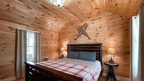 A wooden-paneled bedroom with a bed, two bedside lamps, a small table, and a decorative star on the wall.