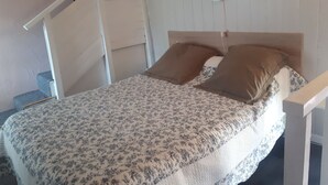 A bed with a floral bedspread, two pillows, a headboard, and a white railing. - lodging the rosemary: implanted in a green frame under the sun of midday. (Le Thoronet)
