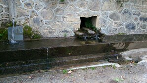 Een stenen muur met een waterpartij, inclusief een kleine waterval en een stenen bak.