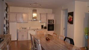 Een moderne keuken met witte kasten, een houten eettafel en een magnetron.