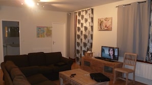 Een woonkamer met een bank, een salontafel, een televisie en een houten kast.