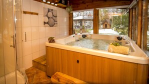 A wooden spa tub with a view of a snowy landscape through large windows.