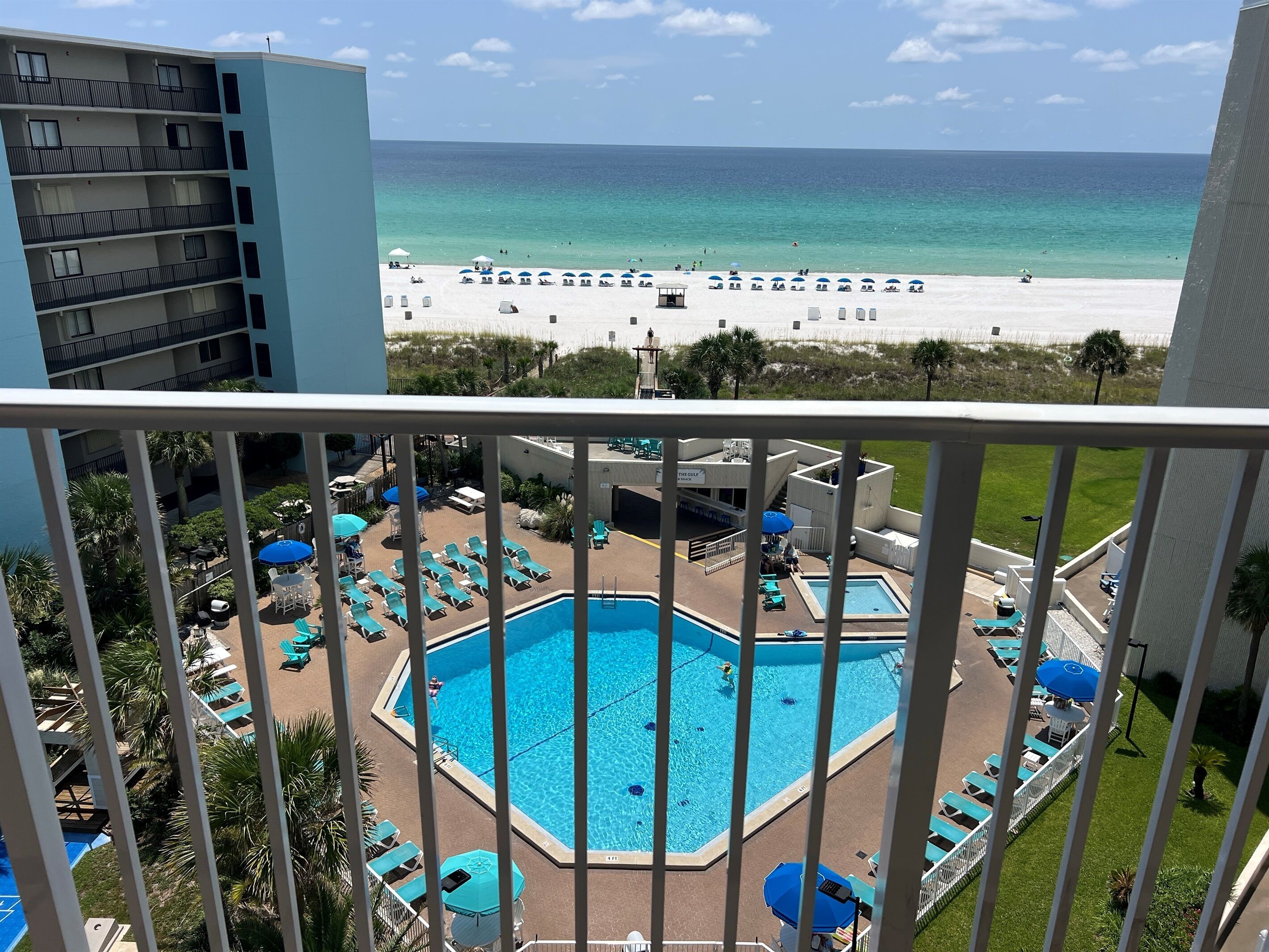Un espace piscine d’hôtel avec vue sur la plage, des chaises longues et des parasols.