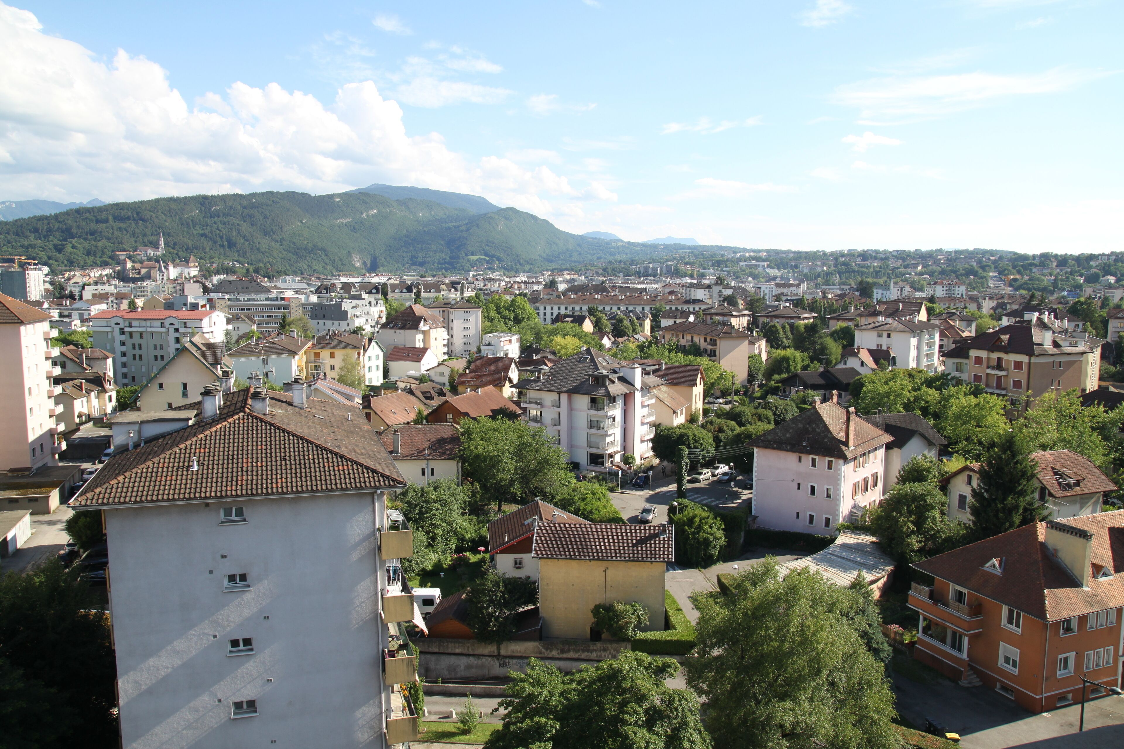 Un quartier résidentiel avec des immeubles, des arbres et une chaîne de montagnes en arrière-plan.