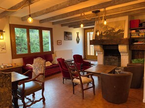 Ein gemütliches Wohnzimmer mit Kamin, Holzmöbeln und großen Fenstern.