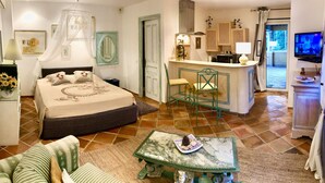 A bedroom with a bed, bedside table, and a nightstand. There is a small kitchenette with a microwave, a sink, and a stove. A television is mounted on the wall. - CHARMING STUDIO 28m2 terrace 22m2 PANORAMA MER / MASSIF DE L'ESTEREL (Théoule-Sur-Mer)