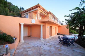 Un bâtiment doté d’un balcon, d’un revêtement de sol en pierre et d’un espace extérieur aménagé pour s’asseoir.