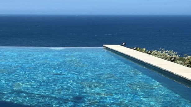 Una piscina aquarmarina de color blau clar amb vista a l'oceà.