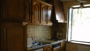 A kitchen with wooden cabinets, a tiled backsplash, a window, and a built-in dishwasher. - Apartment 4 persons (2*) in character house, garden, quiet, GERARDMER (Gérardmer)