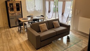 Een moderne woonkamer met een bank, een eettafel en een kast met lades.