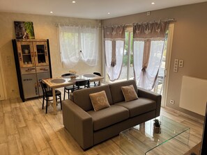 A modern living room with a sofa, dining table, and a cabinet with drawers. - L'OASIS DE BOISSET: 5* VILLA, 3 min from Anduze, private SWIMMING POOL / SPA, 10/14 per (Boisset-Et-Gaujac)