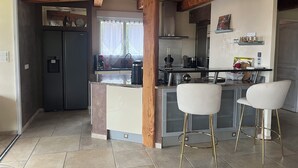 Een moderne keuken met een centraal eiland, barstoelen en houten balken.
