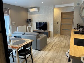 A modern living room with a sofa, TV, and a dining area with a table and chairs. - L'OASIS DE BOISSET: 5* VILLA, 3 min from Anduze, private SWIMMING POOL / SPA, 10/14 per (Boisset-Et-Gaujac)