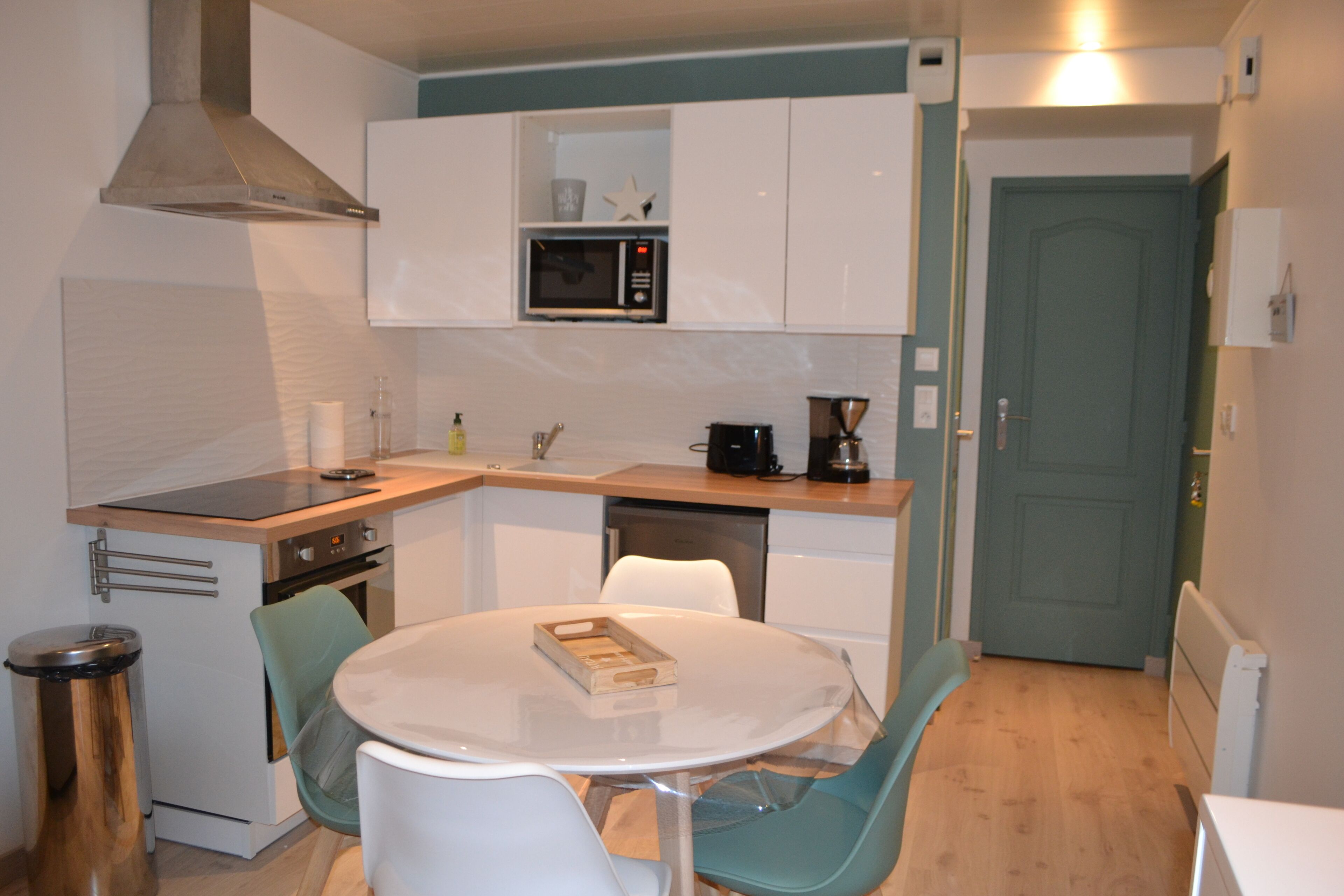 A compact kitchen with a microwave, coffee maker, and a small dining table with chairs.