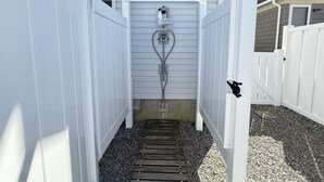 A narrow pathway leading to a white gate with a metal gate handle.