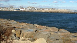 A coastal town with a rocky shoreline and a row of houses in the background.
