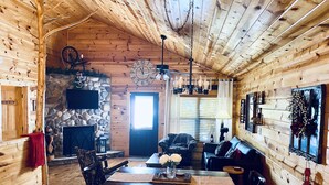 Ein gemütliches Blockhaus-Interieur mit Kamin aus Stein, Holzboden und Steinwand.