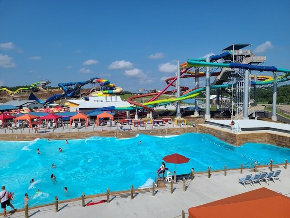 Ein Wasserpark mit einem großen Schwimmbecken, mehreren Wasserrutschen und Liegestühlen.