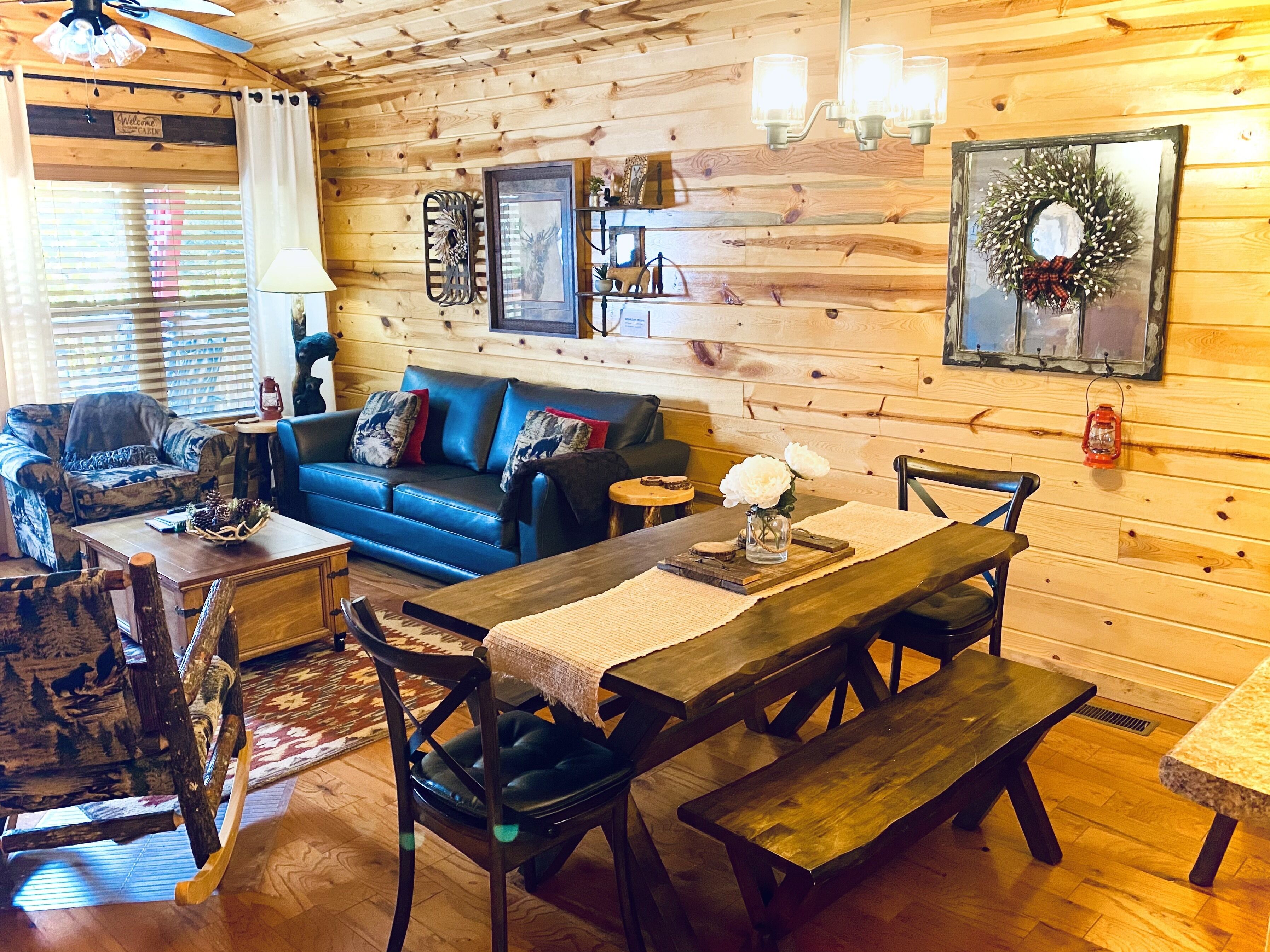 A cozy cabin interior with a blue leather sofa, wooden dining table, and benches.