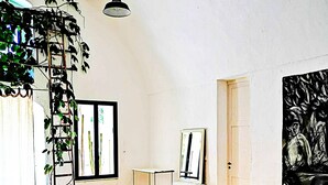 Une pièce avec une table de ping-pong, un plancher en bois, une plante suspendue, un tableau encadré et une peinture au mur.