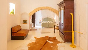 Une pièce comprenant un canapé, une armoire en bois, un tapis en peau de vache et un lit à baldaquin.