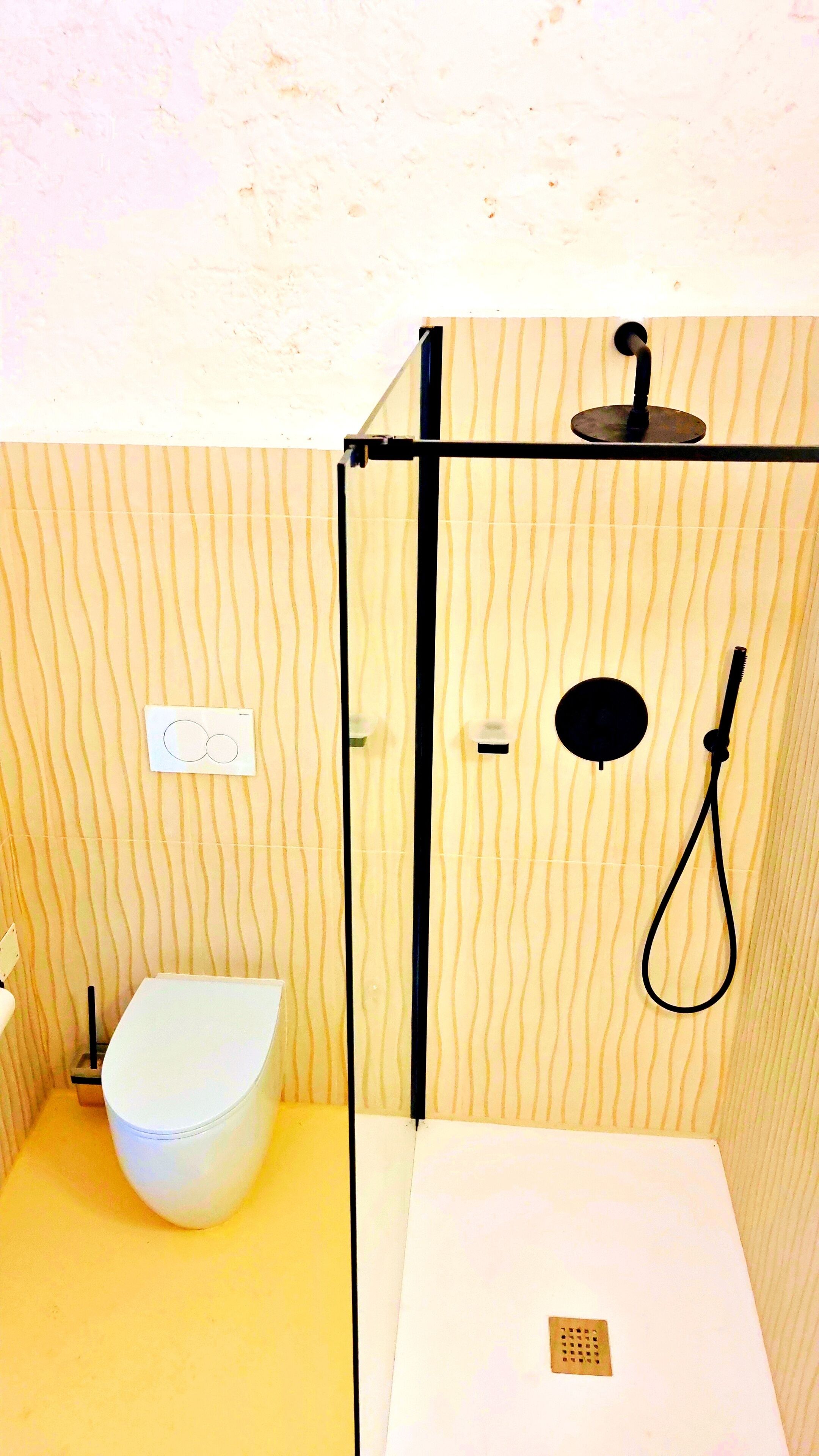 A compact bathroom with a toilet, a shower area, and a sink.