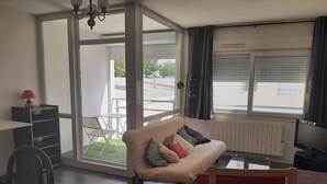 A living room with a sofa, a dining table, a chair, and a TV. - Pleasant T2 excellent location near the old port secure parking, Wifi (La Rochelle)